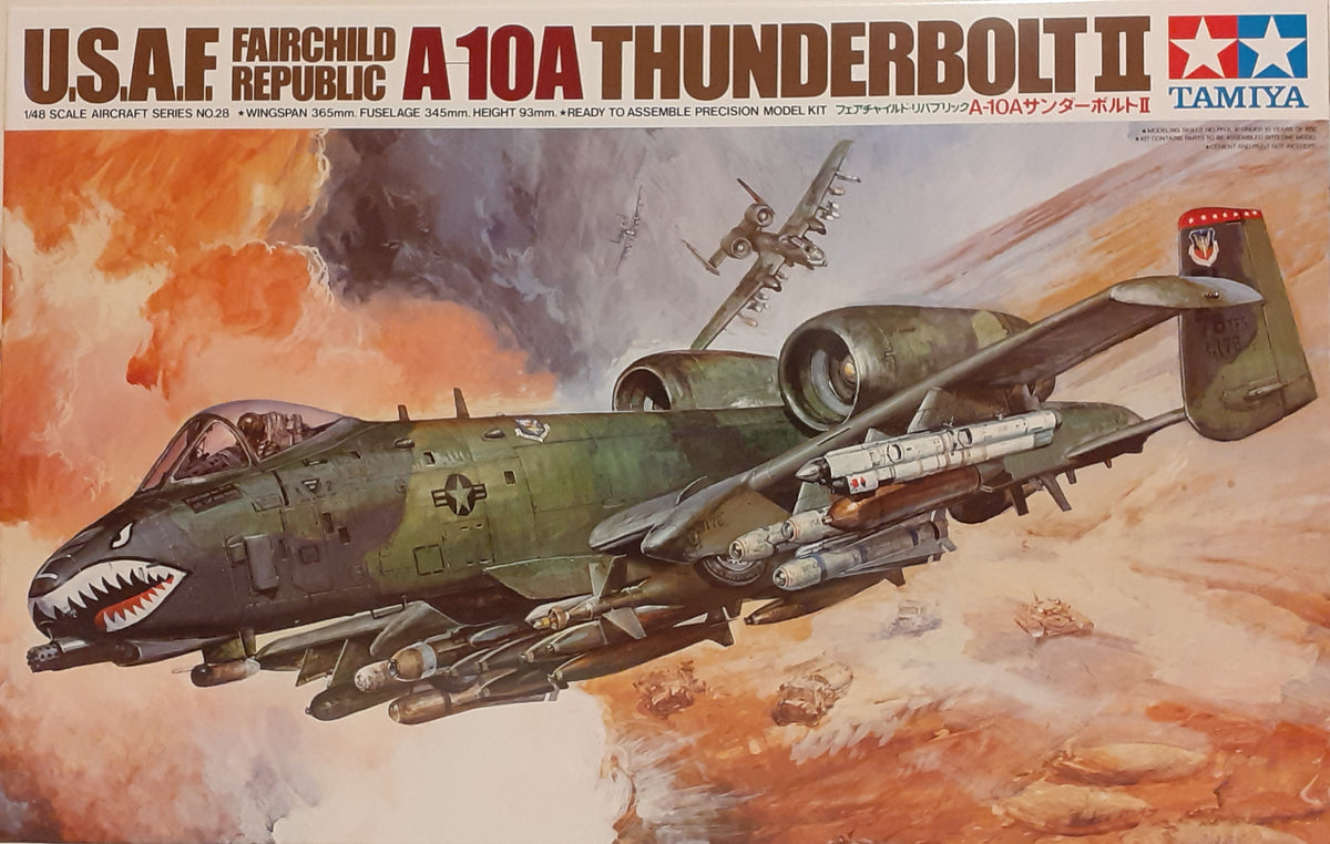 A model kit of the US Air Force A-10A Thunderbolt II aircraft, featuring a green camouflage design, equipped with missiles and bombs, against a simulated battle backdrop.