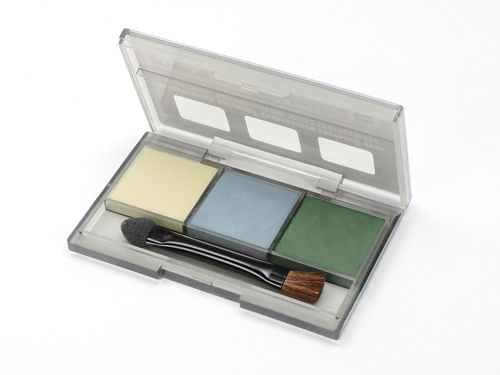 A set of Tamiya weathering master pigments with a brush, including yellow, gray, and green shades, displayed in a clear plastic case.